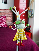 Child's coat rack with hanging stuffed animal in front of a red bed