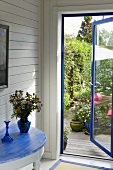 Geschwungener Wandtisch mit blauer Holzplatte und Blick durch offene Tür in Garten