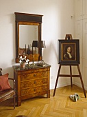 Artwork on easel next to chest of drawers with marble top