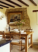 Dining room with a wooden table and chairs, artwork on an exposed stone wall.