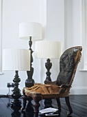 Three lamps set on the floor next to an old leather chair thatÕs lost its upholstery