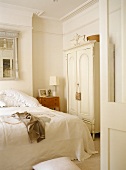 Freestanding wardrobe next to bed in neutral colour bedroom