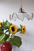 Pendant light in front of sunflowers in red vase