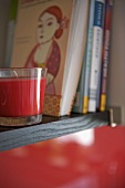 Red candle and books on shelf