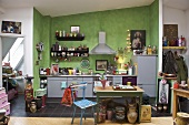 Moderne Küche mit grüner Wand und Möbeln im Stilmix