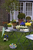 Osterdekoration auf Gartentisch und Stuhl mit Frühlingsblumen