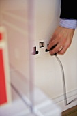 Person putting plug into electrical wall socket