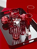 A detail of red glasses set on a black lacquer tray