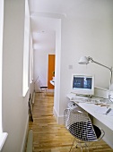A modern, white office area with desk, computer, wire chair, wood floor,
