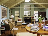 A country style, traditional sitting room, panelled slanted roof, fireplace, beige sofa and chairs, round polished table,