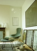 Retro style chair and footstool next to large pieces of artwork propped against wall