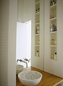Modernes Bad mit Waschschüssel vor Spiegel und Einbauregal mit Badutensilien