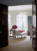 A view through an open door into a traditional sitting room, upholstered sofa, French windows