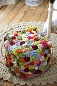 A stool made of colourful crocheted flowers on a crocheted rug