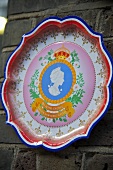 A painted enamel wall plate on a stone wall
