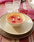 Pink floating candles in a porcelain bowl on a white plate