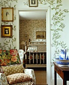 A reading chair with cushions next to an open door and a view into a bedroom in a country house