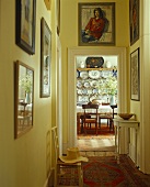 A yellow hallway hung with pictures and an open door with a view into a dining room