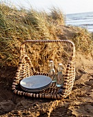 A picnic basket in the sand with a sea view