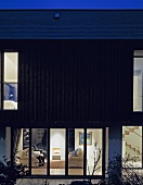 Neubauhaus mit beleuchtetem Wohnraum in Nachtstimmung