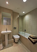 A modern bathroom with spot lights and light brown wall and floor tiles