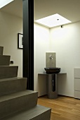 Stairs in a living room with a wash basin in the corner