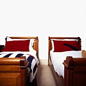 Zwei Einzelbetten mit roten Kissen in einem weissen Schlafzimmer