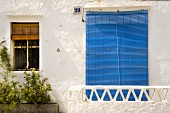Weisser Balkon mit blauer Fensterjalousie an einem Spanischen Haus