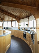 Holzdecke im kreisförmigen Raum mit offener Küche aus hellem Holz