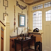 Diele mit Fenster mit Glasbemalung neben und über der Tür, mit einer Konsole und mit Decoupage-Ghirlanden an der Wand