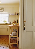 Blick in eine cremefarbene Küche mit beweglichem Arbeitstisch