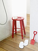 Roter Hocker, Schaufel und weiße Flip-Flops in einer Dusche