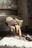 A cosy seating area in an attic - a bucket chair with a blanket and a cushion with a fur rug on the floor