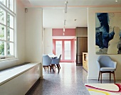 An open anteroom with a Bauhaus-style chair under a picture and a view of a dining area