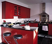 Offene Küche in Rot mit Barhockern aus schwarzem Leder und Chrom vor Theke