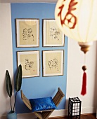 Bildersammlung auf hellblauer Wand und rustikaler Holzhocker mit blauem Kissen