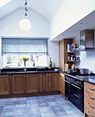 Moderne Küche mit Holzfronten und grauem Fliesenboden im Dachgeschoss