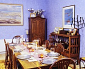 Gedeckter Esstisch und antike Möbel im violett getönten Zimmer