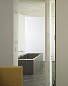 A view into a bathroom with a grey, cubic bathtub
