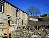 A renovated country house with a natural stone facade and a garden wall