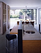 An island kitchen counter with a stone work surface and a sink in an open-plan living room
