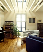Graues und blaues Sofa korrespondiert mit abstrakter Malerei in modernem Wohnzimmer mit weissen Holzbalken auf Galerieebene