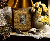 Stillleben mit stoffgerahmtem, viktorianischem Foto und gelben Rosen in Porzellanvasen