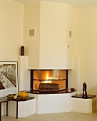 Brennender Kamin mit Skulptur eines liebenden Paares auf schwarzer Marmorplatter der gemauerten Bänke in modernem Wohnzimmer