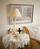 Lampe auf kleinem Tisch mit Silberkanne und Frauenbüste zwischen aufgebauschter Spitzendecke