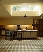 Grosses Oberlicht über moderner, offener Küche mit Barhockern aus Holz an Frühstücksbar und grau-weißem Schachbrett-Fliesenboden