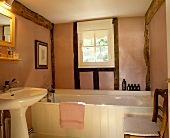 Holzverkleidete Wanne in Bad mit rosefarbener Wandausfachung zwischen Fachwerkbalken