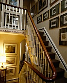 Bildergalerie über antiker Holztreppe mit Teppich, zierlichen Geländerstäben und Mahagoni-Handlauf in französischem Landhaus