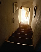Sonnenlicht am Ende eines schmalen Treppenabgangs mit Terracotta-Stufen in altem, französischem Landhaus
