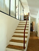 Rustikaler, gemauerter Treppenaufgang in Gangflucht mit moderner Glastrennwand und Terracotta-Kleinstein auf Stufen und Boden